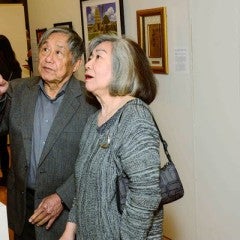 An elderly Asian American couple looks at an exhibit at “Our Vibrant AAPI Community."