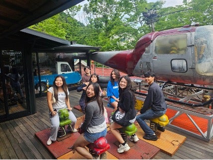 Students posing next to an old helicoptor